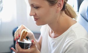 woman holding sandwiches in hand in cabin during airplane flight