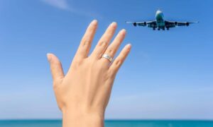 Female hand with ring and airplane in the background