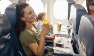 Happy passenger drinking coffee on airplane