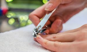 woman cutting nails with nail clippers
