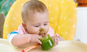 Little baby is eating broccoli vegetable puree