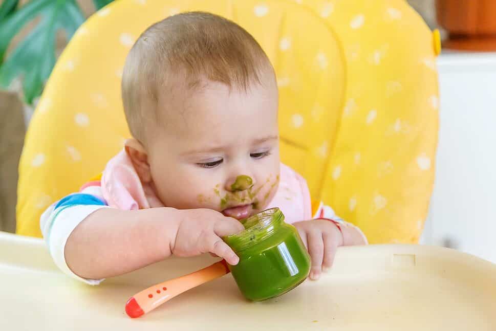 Little baby is eating broccoli vegetable puree