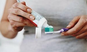 woman squeezing toothpaste onto her toothbrush