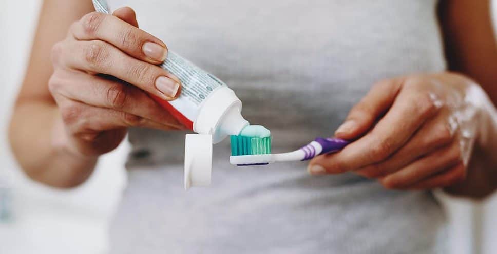 woman squeezing toothpaste onto her toothbrush
