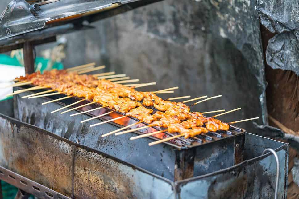 Thai style pork skewers on a grill with a hot fire