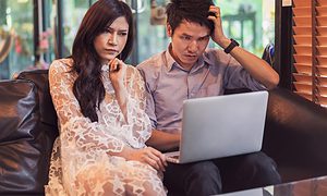 stressed thai man and woman using laptop in cafe in Thailand
