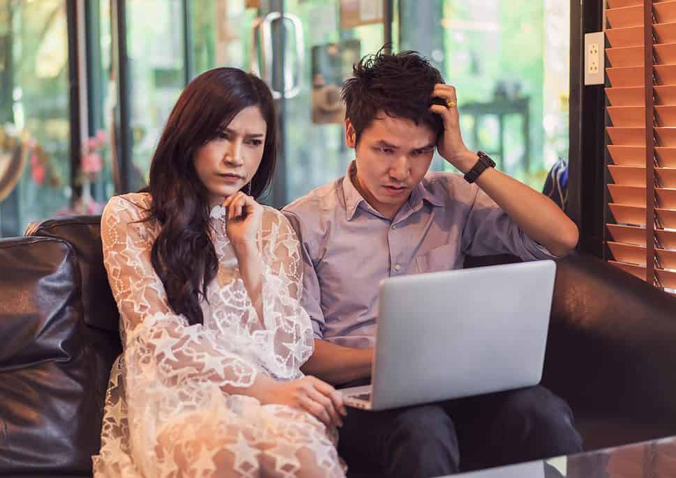 stressed thai man and woman using laptop in cafe in Thailand